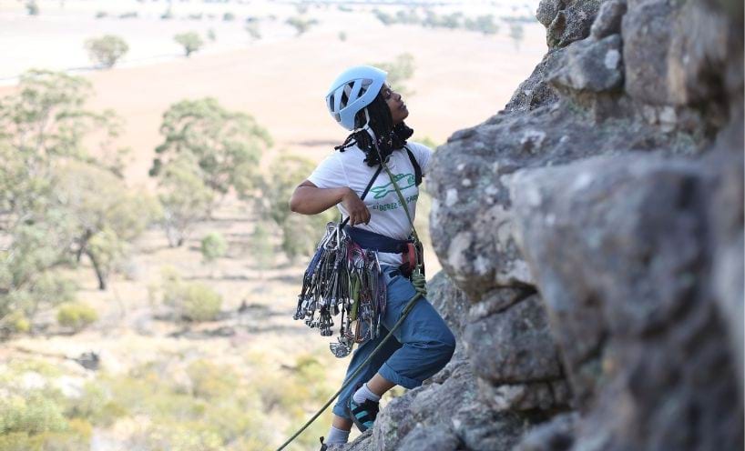 Camp participants scaling rock face