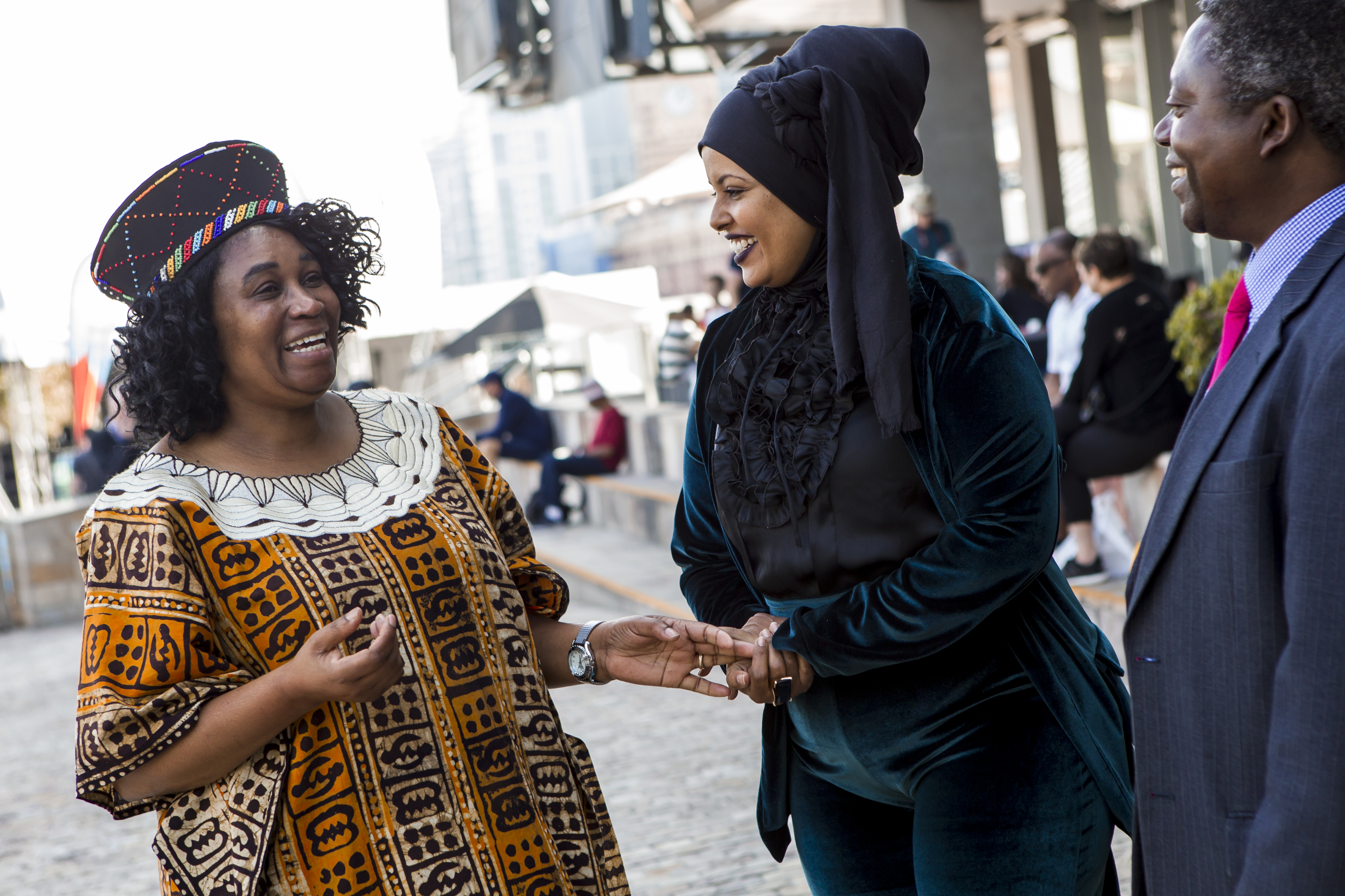 Three people of African background speaking to each other.