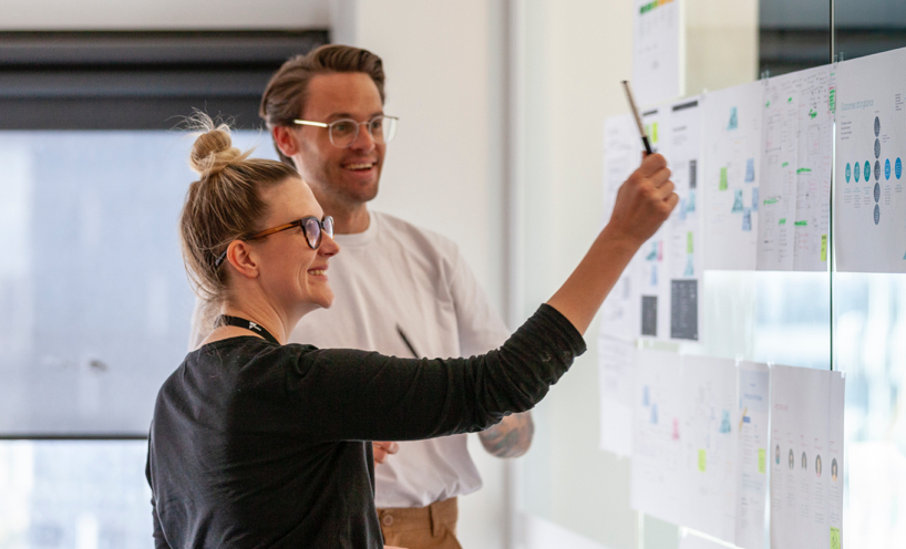 Man and woman standing in front of notes on office wall