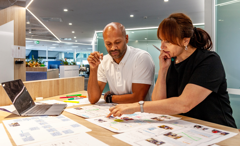 Man and woman sitting at table in office discussing work