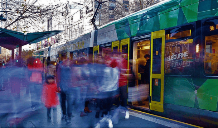 Passengers disembark from a busy tram in the Melbourne CBD