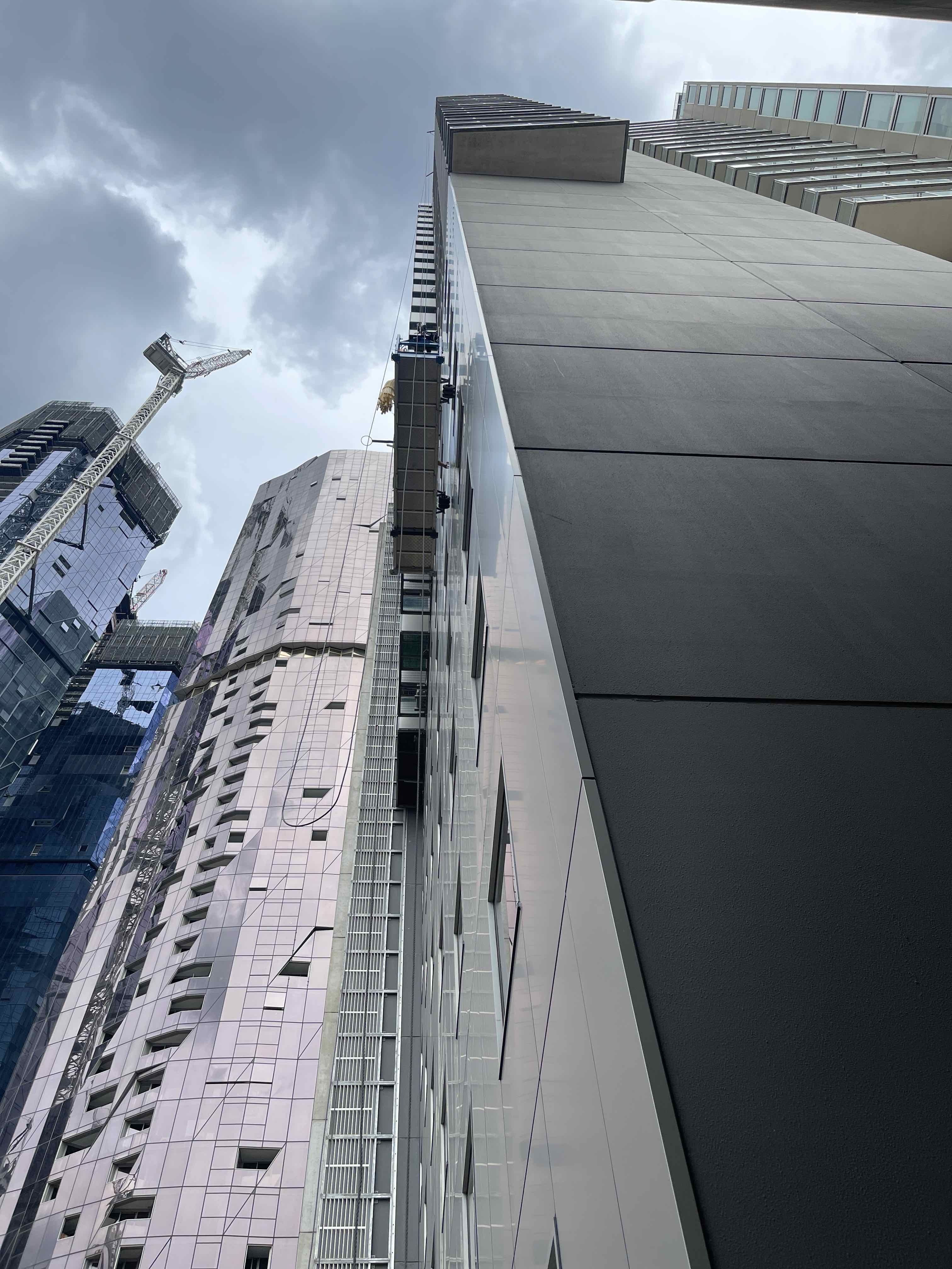 Ground view looking up at people working on a platform half way up a high rise building