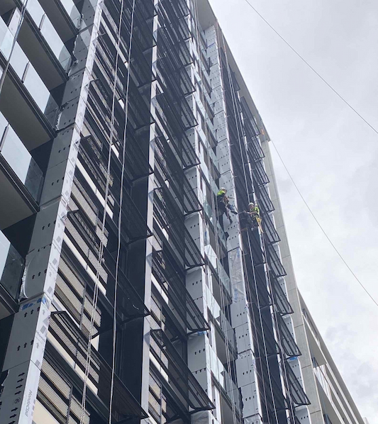 Workers using abseils to rectify cladding panels