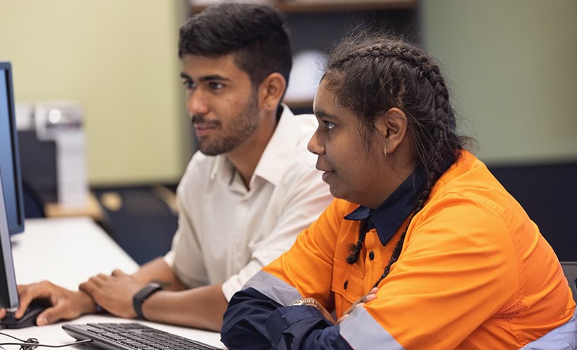 Teacher instructing engineering apprentice at a computer