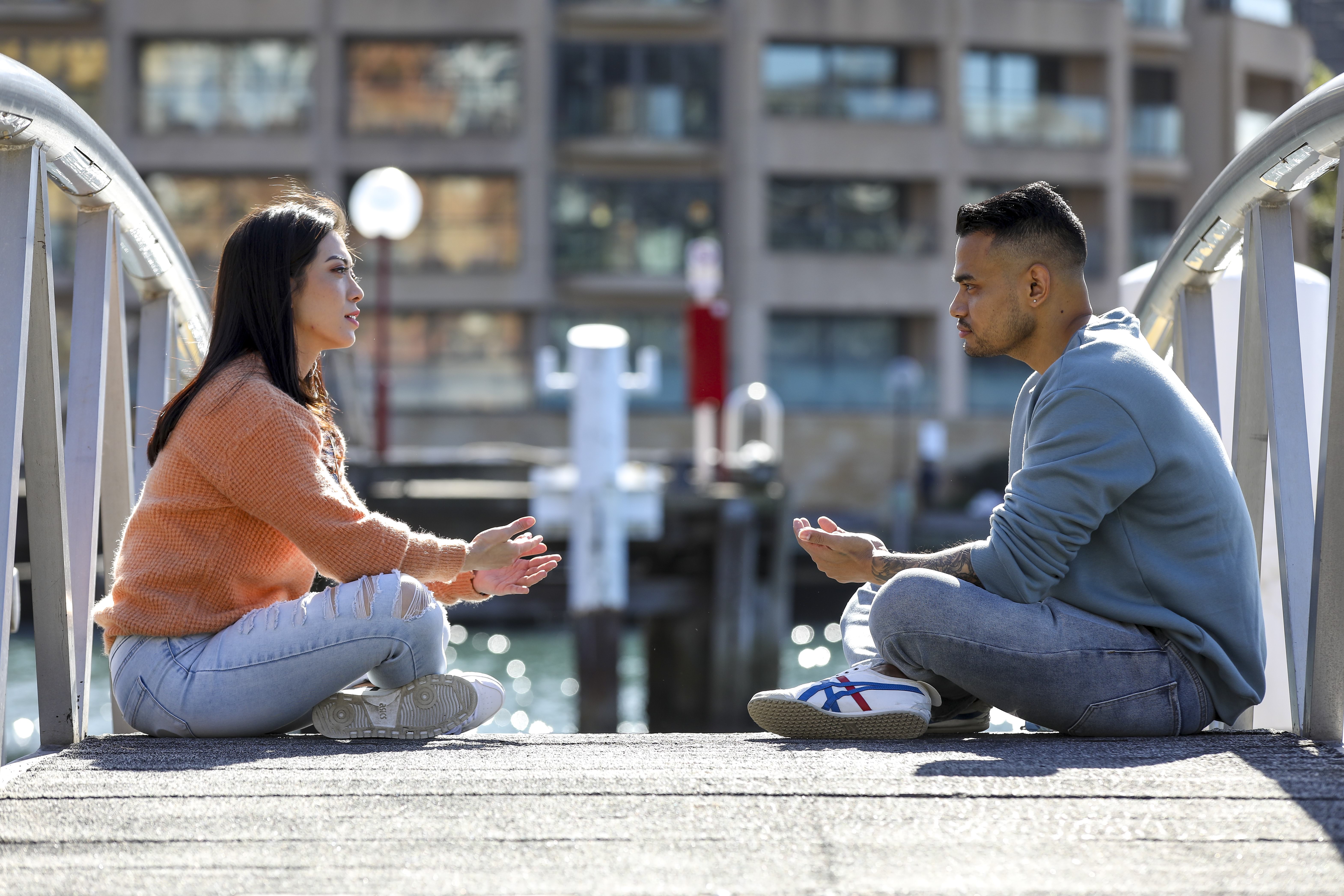 A woman and man sit cross legged facing each other talking 