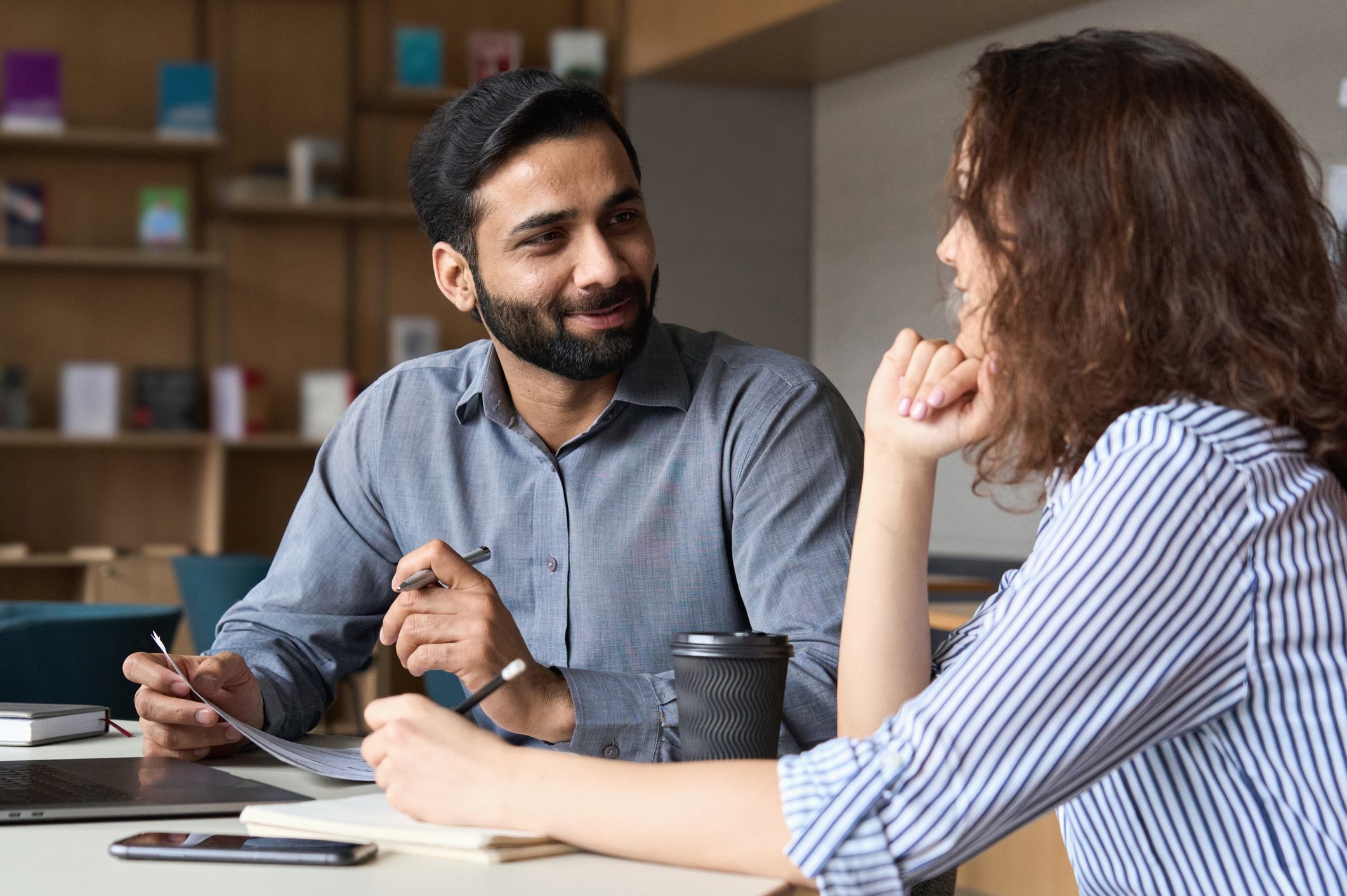 A coach and early childhood professional sit together, having a friendly discussion