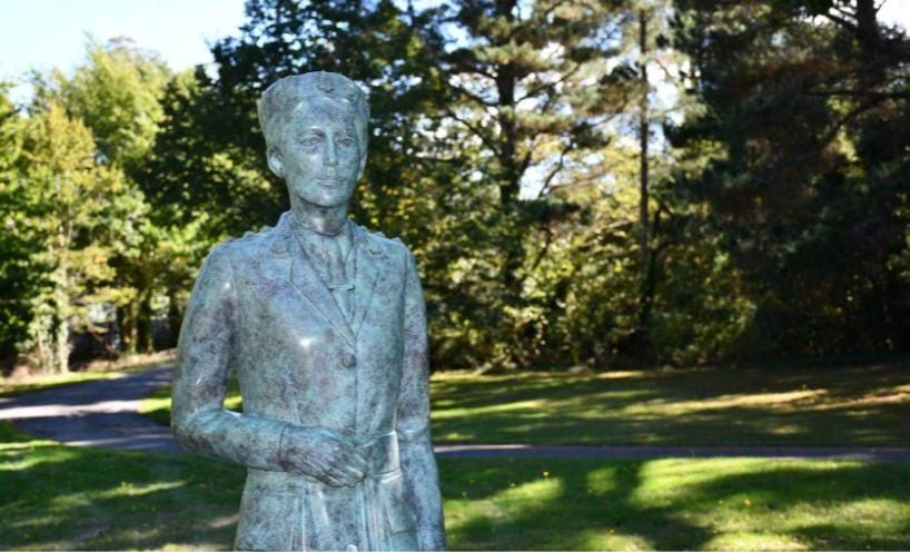 The bronze statue of Dr Vera Scantlebury Brown OBE in the green garden surrounds, in Linton