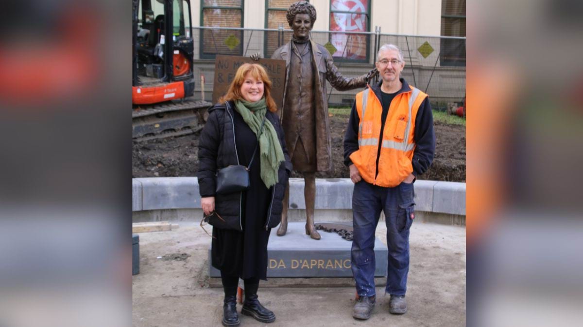 Sculptor Jennifer Mann and Cameron from the foundry with the bronze statue of Zelda D'Aprano in front of the Victorian Trades Hall.