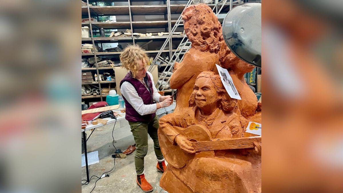 An artist at work on the sculpture, carving the clay.