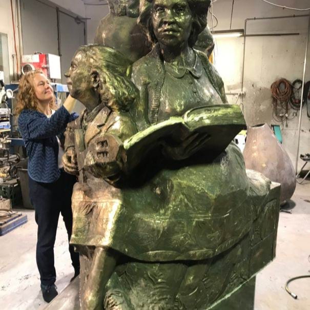 The artist is looking at the details on the bronze statue in the workshop.