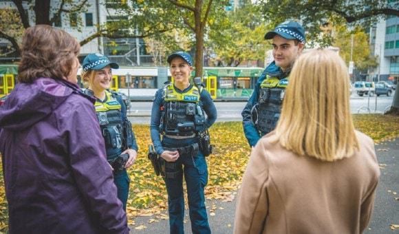 A photo of three police officers talking to two women on a street in Melbourne.