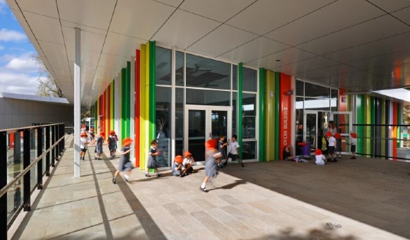 Primary school children playing outside the entrance of a school.