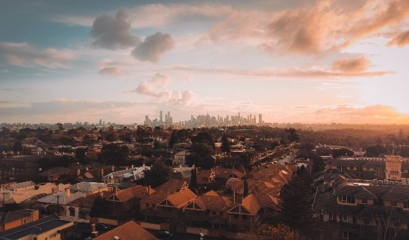 A rooftop photo of Melbourne looking over the roofs of houses and showing the CBD in the distance.