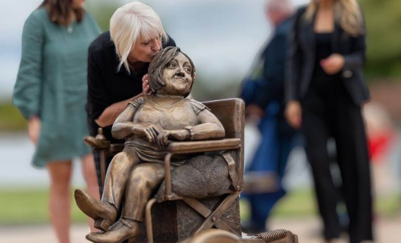 Lynne Young, Stella Young's mother, kisses the of the statue of Stella at the Remembering Stella Young statue unveiling.