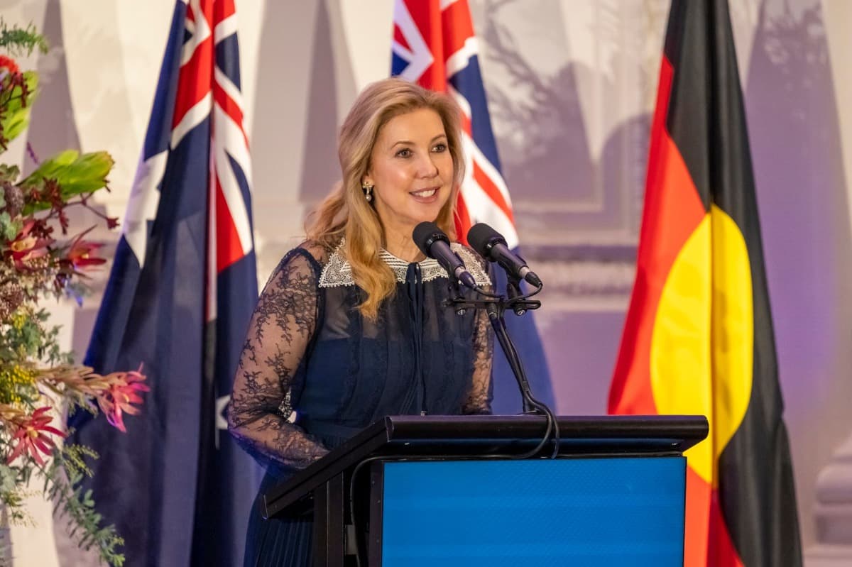 A woman stands at a podium speaking into a microphone. 