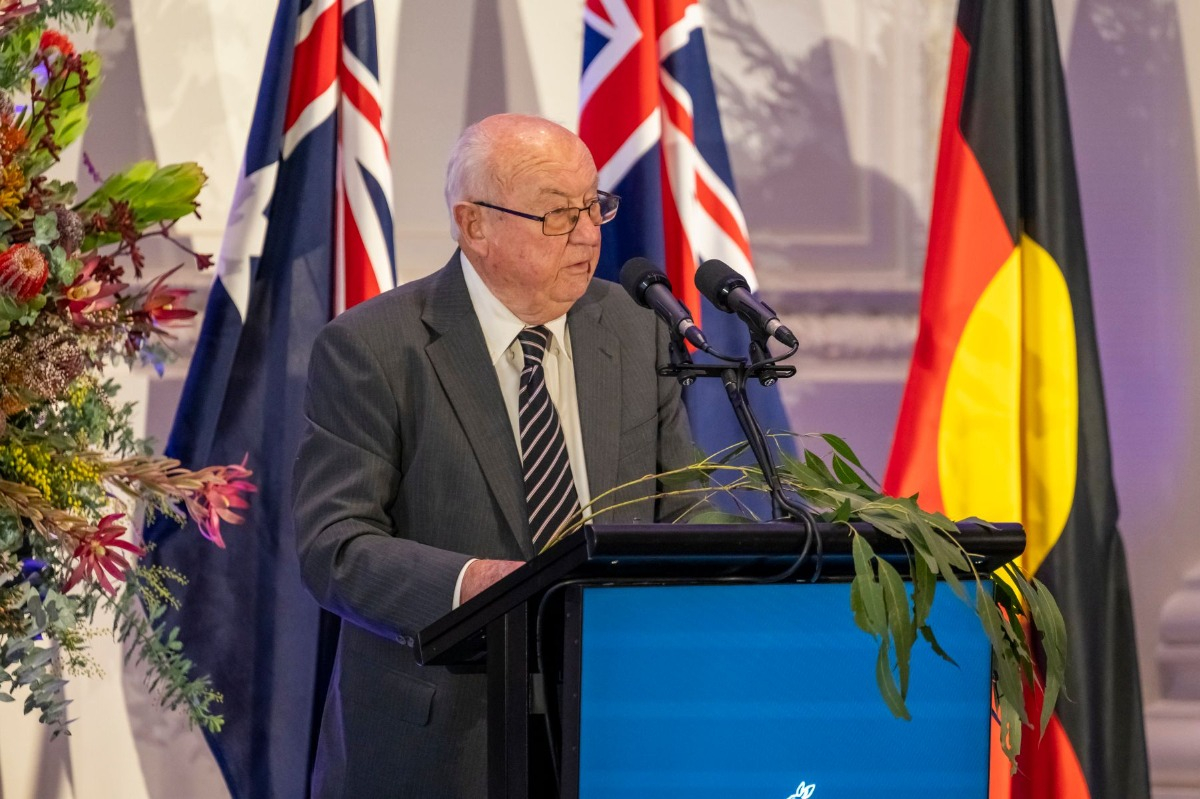 A man stands at a podium speaking into a microphone. 