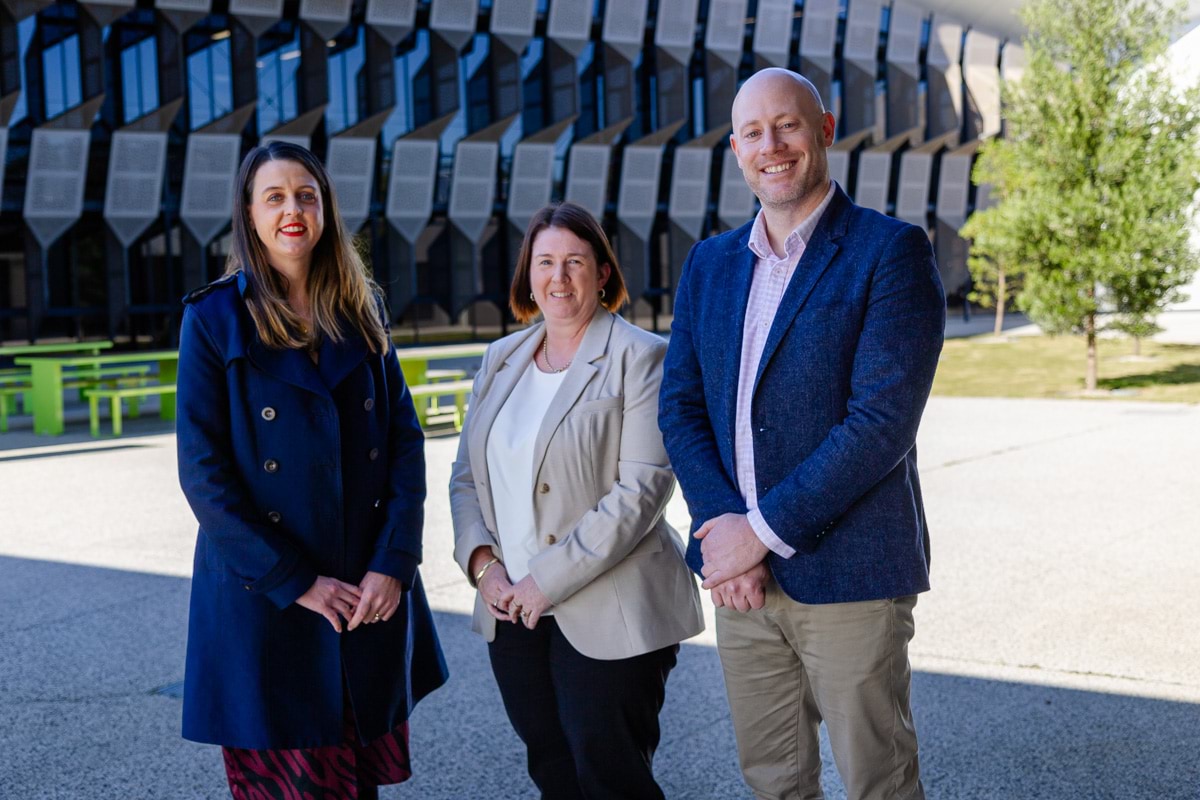 Three members from TAFE Gippsland standing outside campus in business attire and formal pose