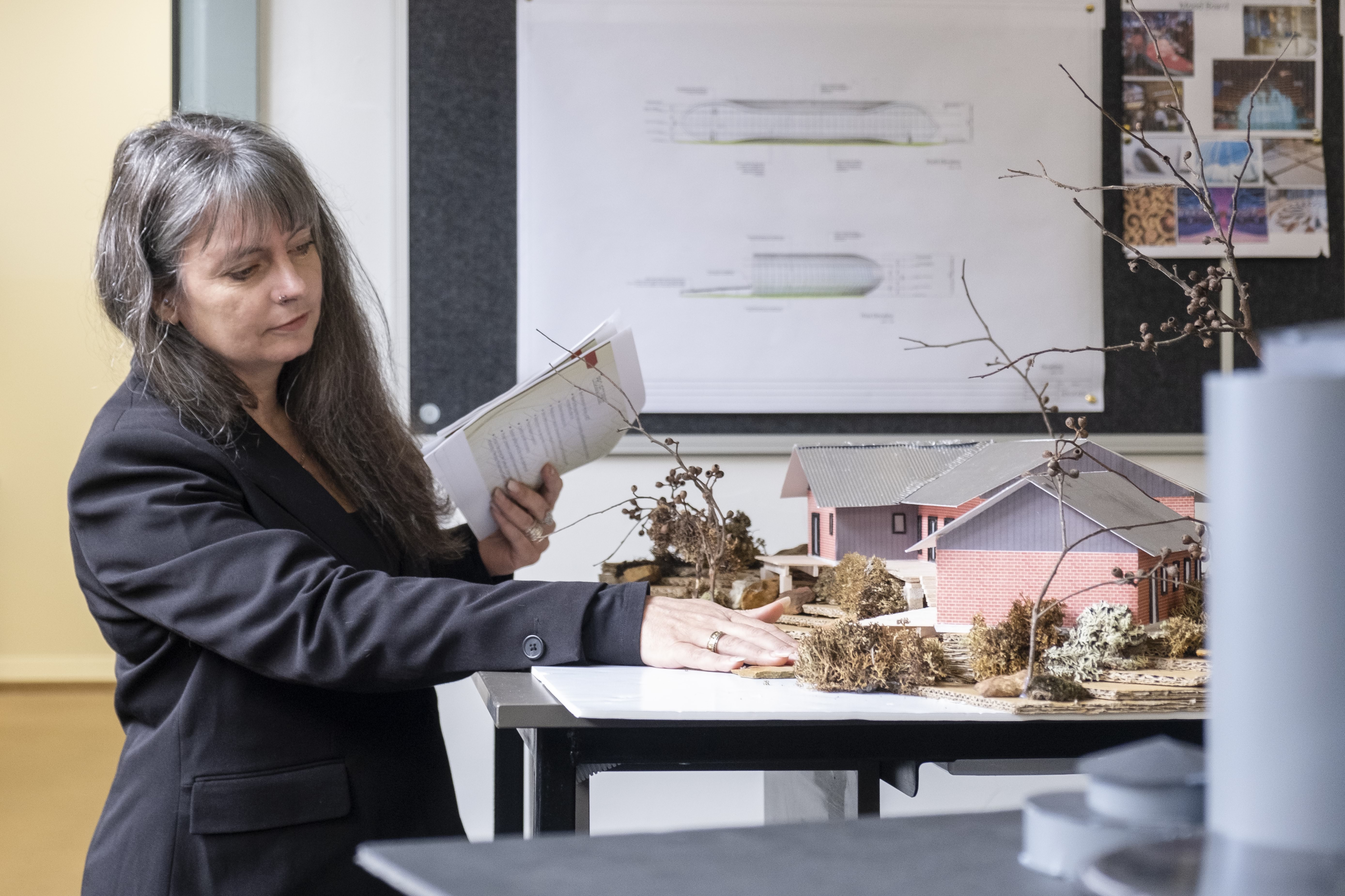 Victorian Training Awards 2023 Vocational Student of the Year winner Barbara Muller looking at an architectural building table model with papers in her hand