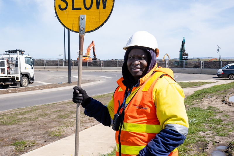 Victorian Learn Local Awards 2022 Pre-accredited Learner winner Felimon at work on the road holding a 'slow' traffic sign.