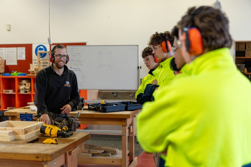 Teacher teaching students carpentry at TAFE ion woodwork classroom.