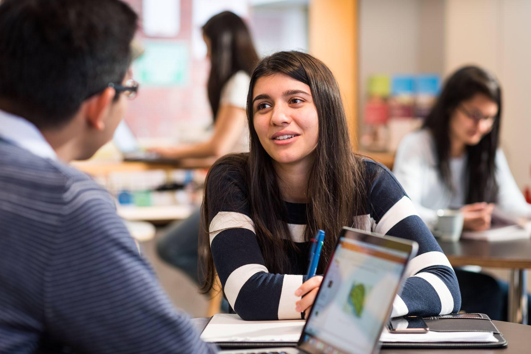 Students sitting in a room talking.