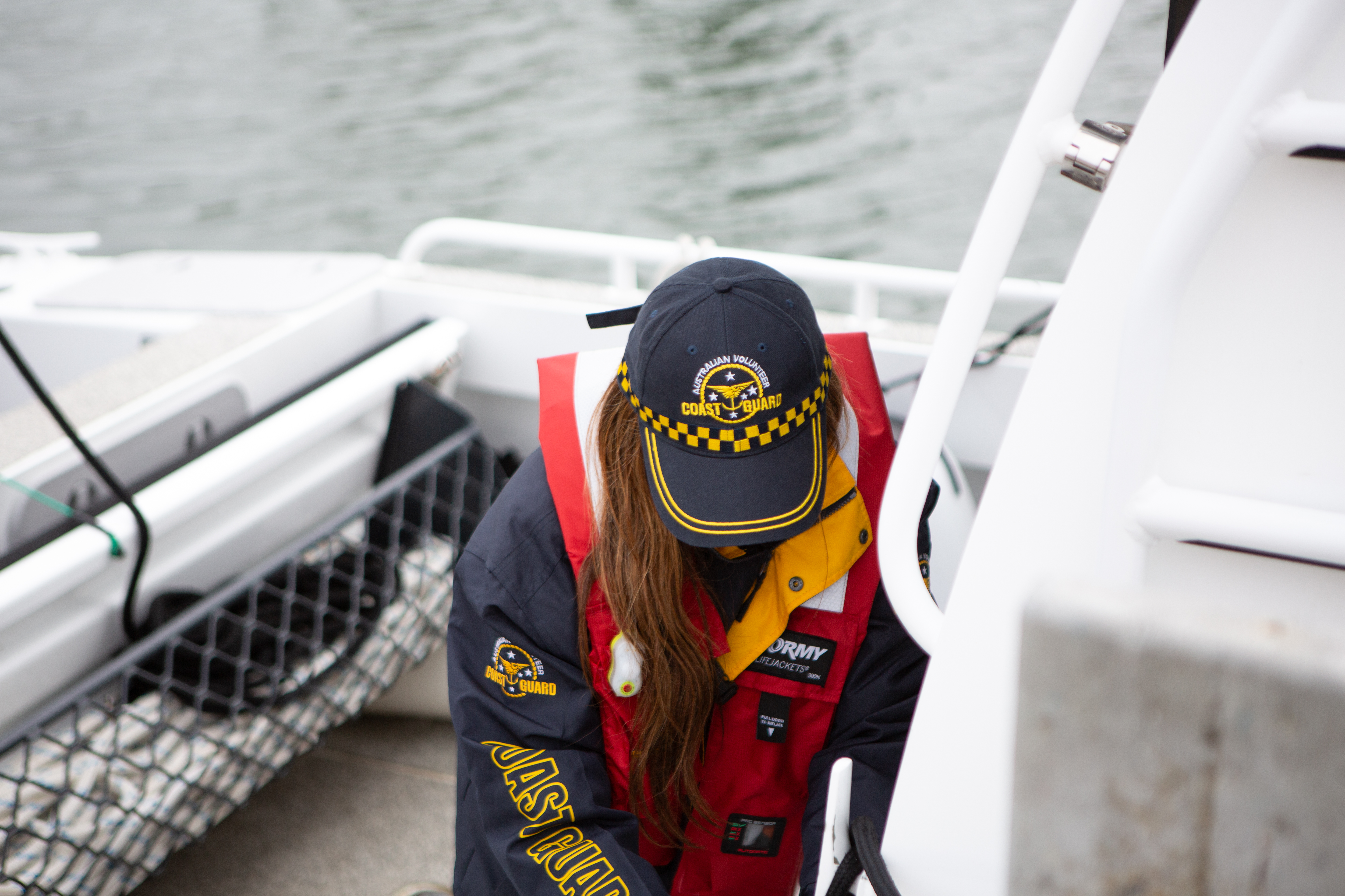 Image shows a MSAR crew member with her head lowered. On her cap, you can read the words: Australian Volunteer Coast Guard.