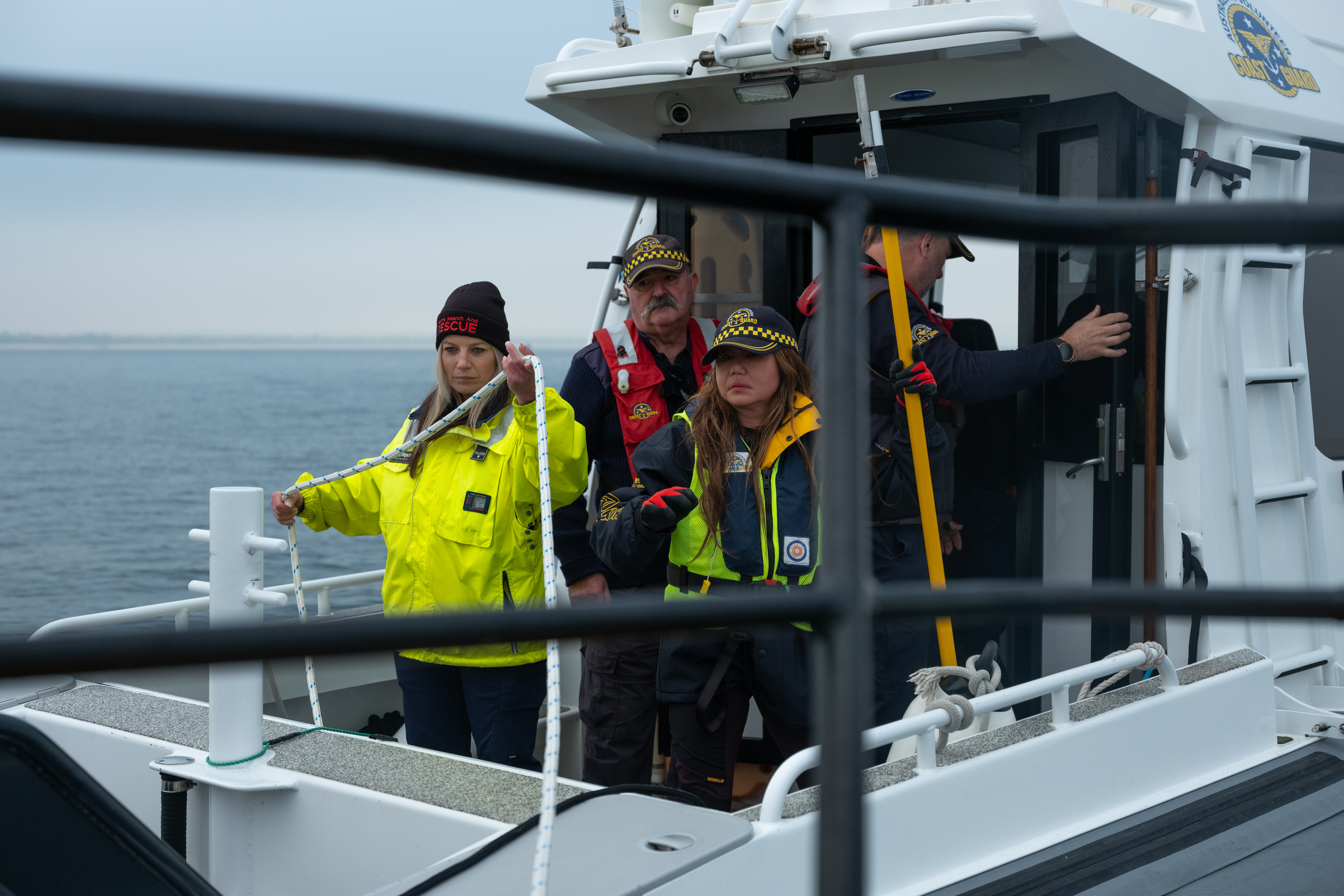 Image shows an MSAR crew standing on the back of a boat, preparing to throw a rope to the pier.