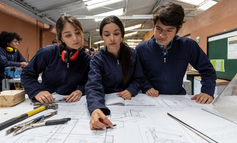 Three young students looking at drafting documents together