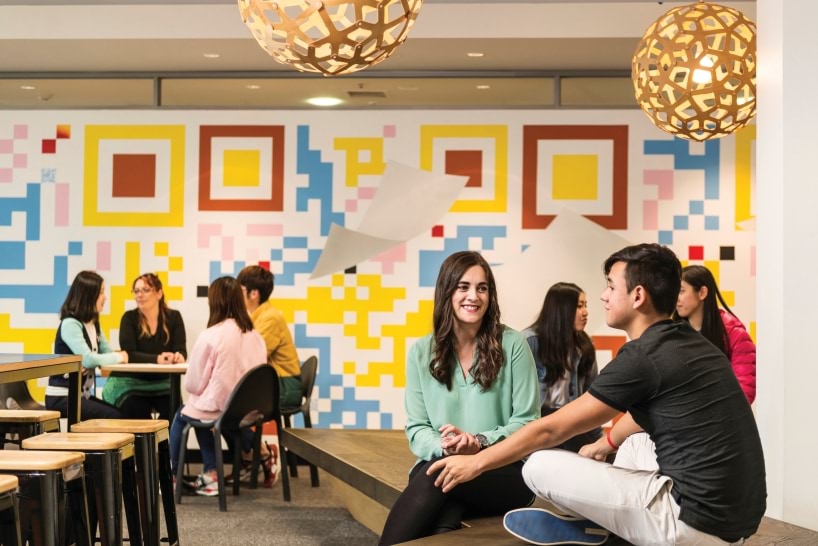 Students sitting and talking in a colourful room.