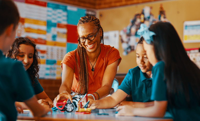 Female teacher sitting with four primary school aged children at a table