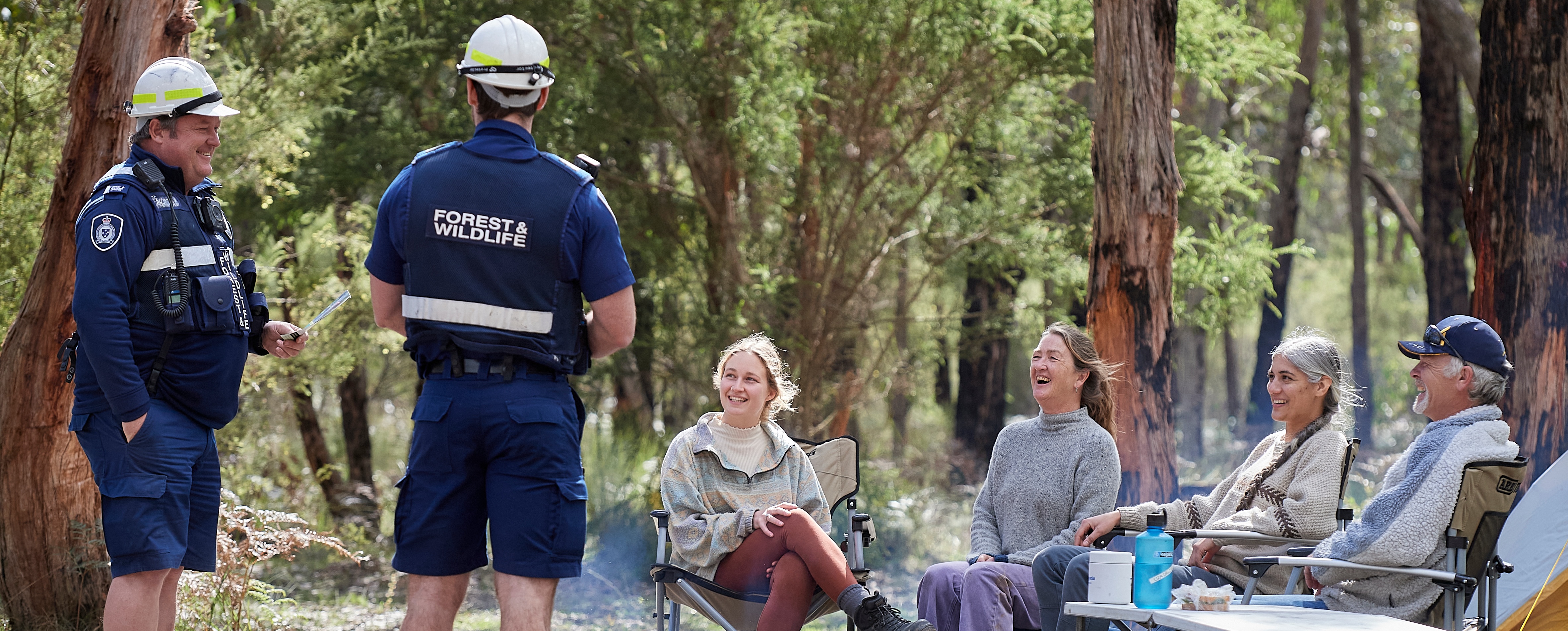 Photo of two Forest and Wildlife officers chatting with four campers