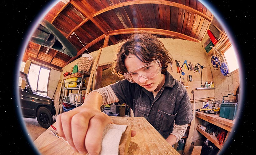 High school student sanding some wood in class