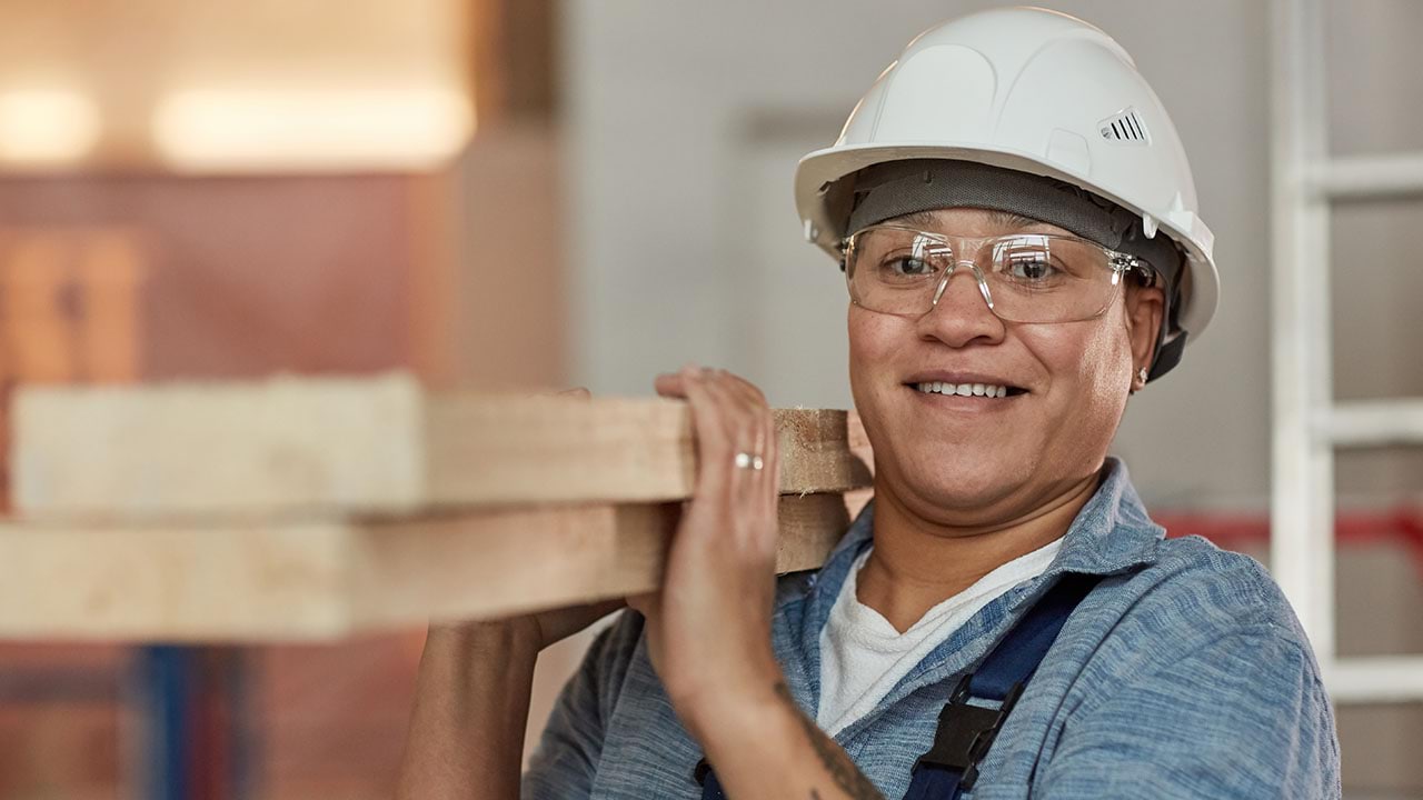 Person in hard-hat carrying planks of wood