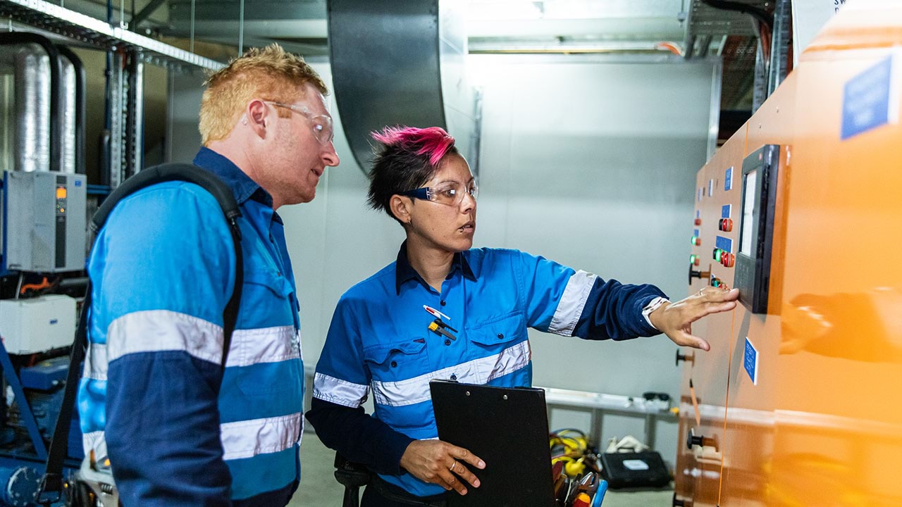 Two workers programming building services panel