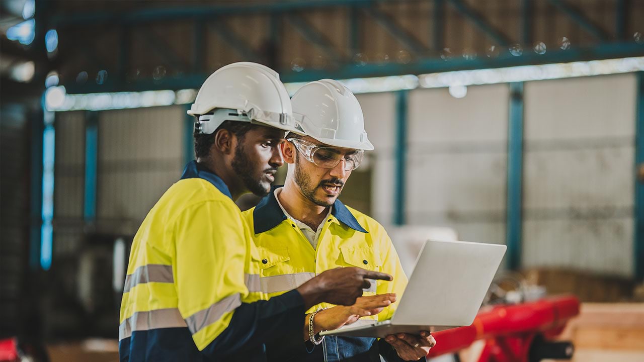 Two people looking into laptop in construction setting