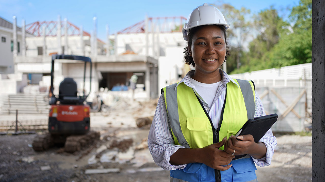 Person wearing a hard hat and holding device in a construction site