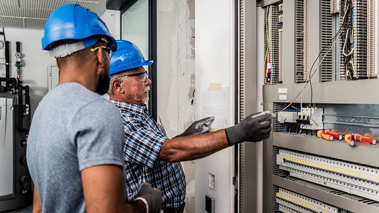 Two people working on powerboard of building