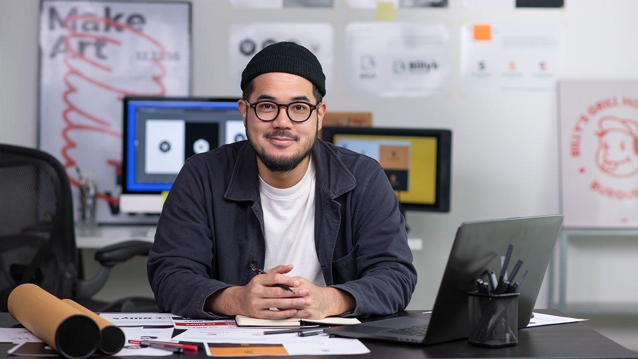 Person at desk in a digital art studio with computer screens in background