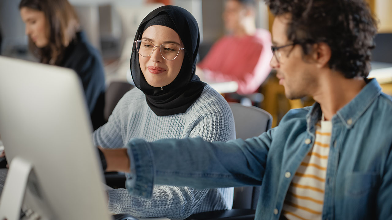 Two people looking into computer