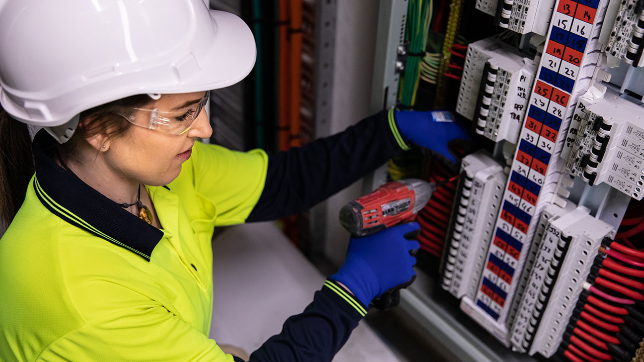 Electrician working on power box with cables