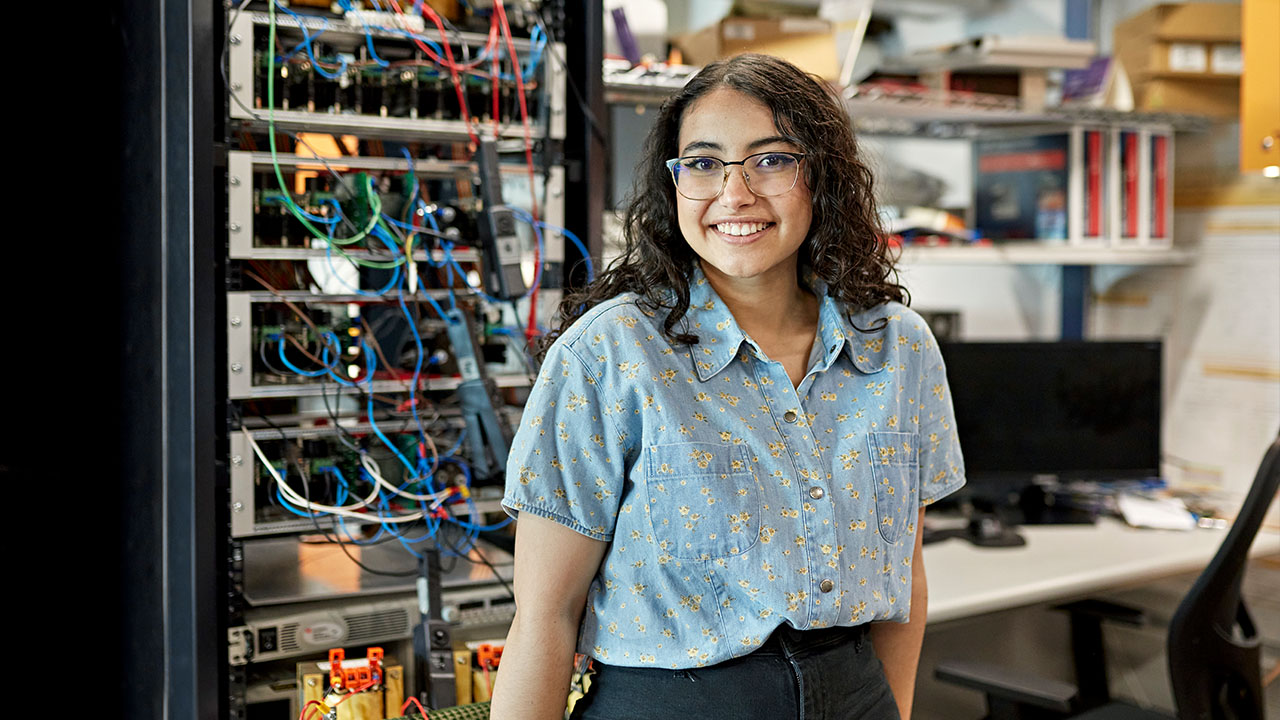 Person standing in front of computer networking cabinet