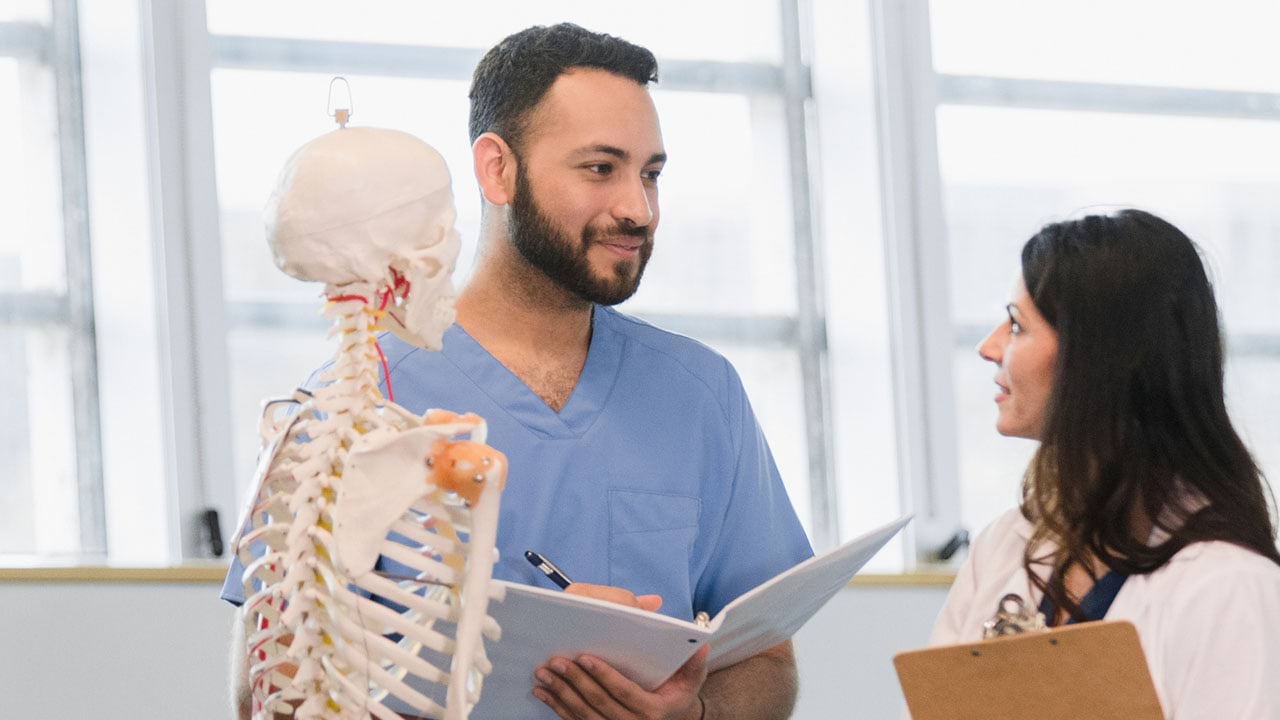 Health care workers in training setting with model skeleton