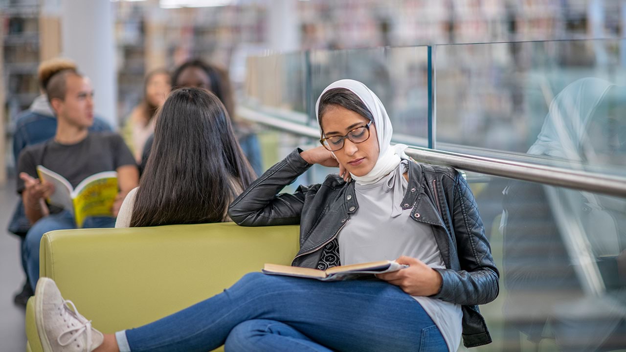 Person reading a book in library setting