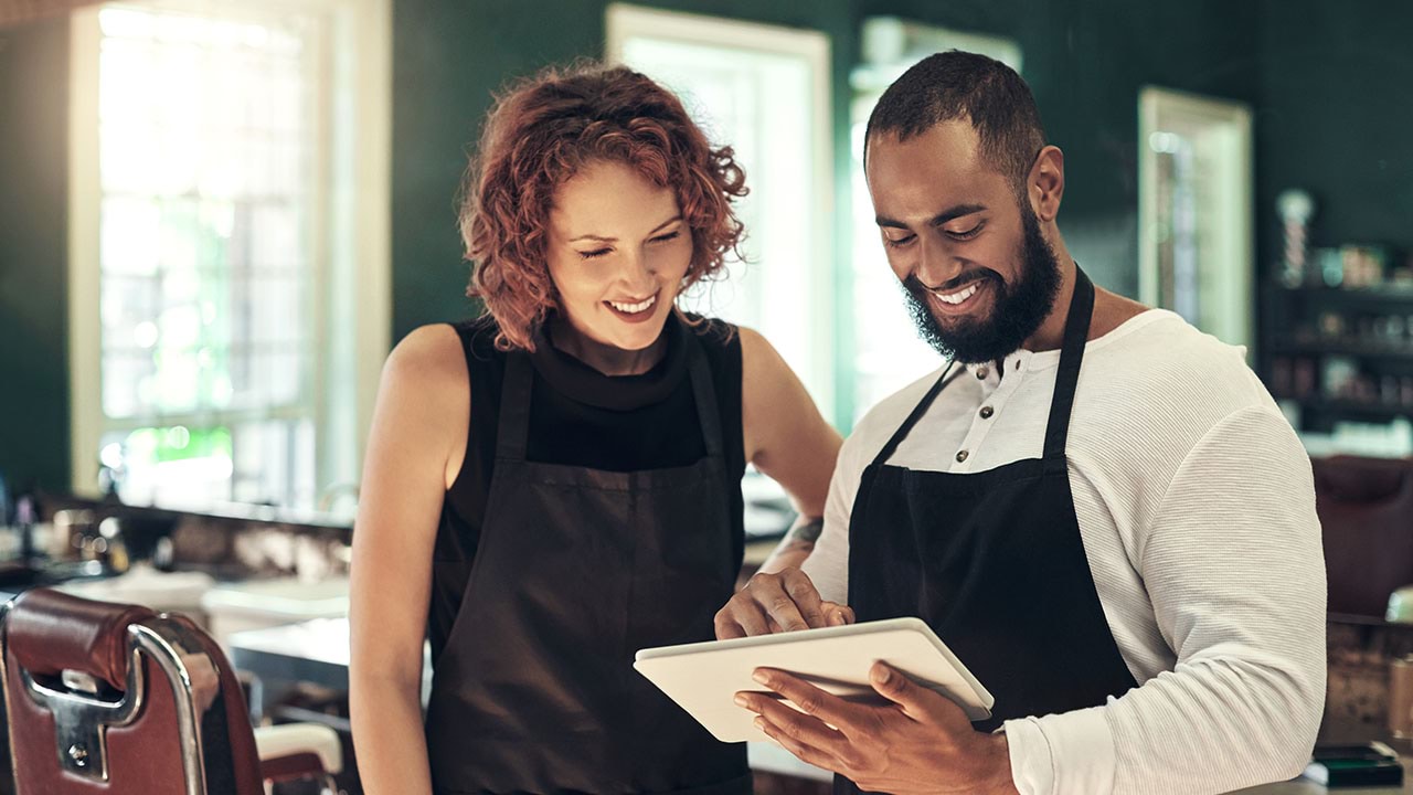 Two hairdressers looking at a device