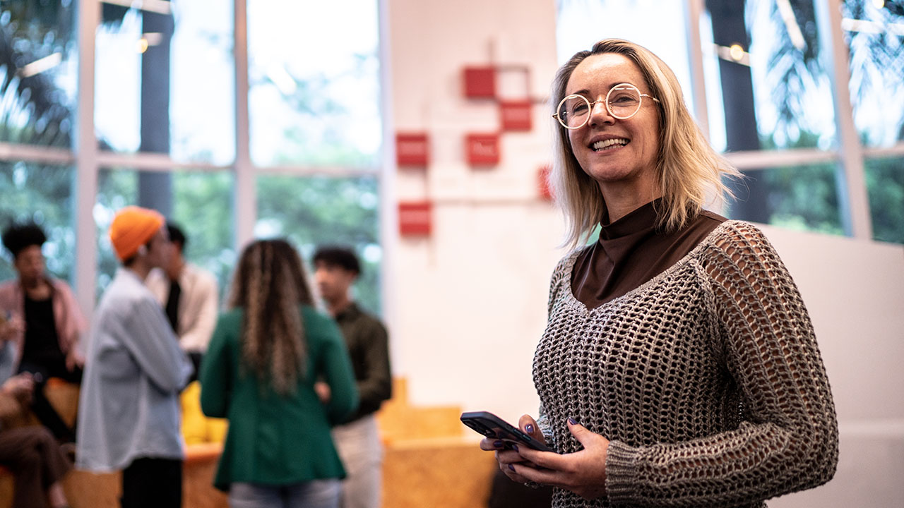 Person holding a device in education space with a group of youths in background