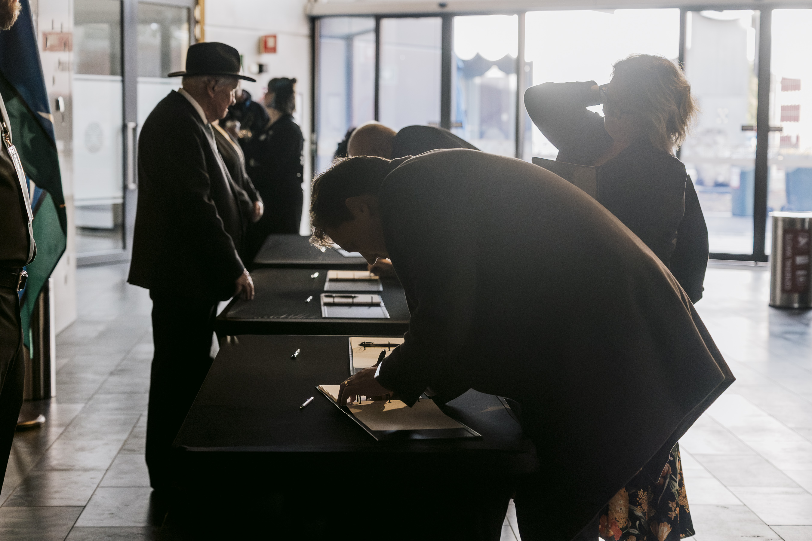 A person in a dark jacket signs a book. 