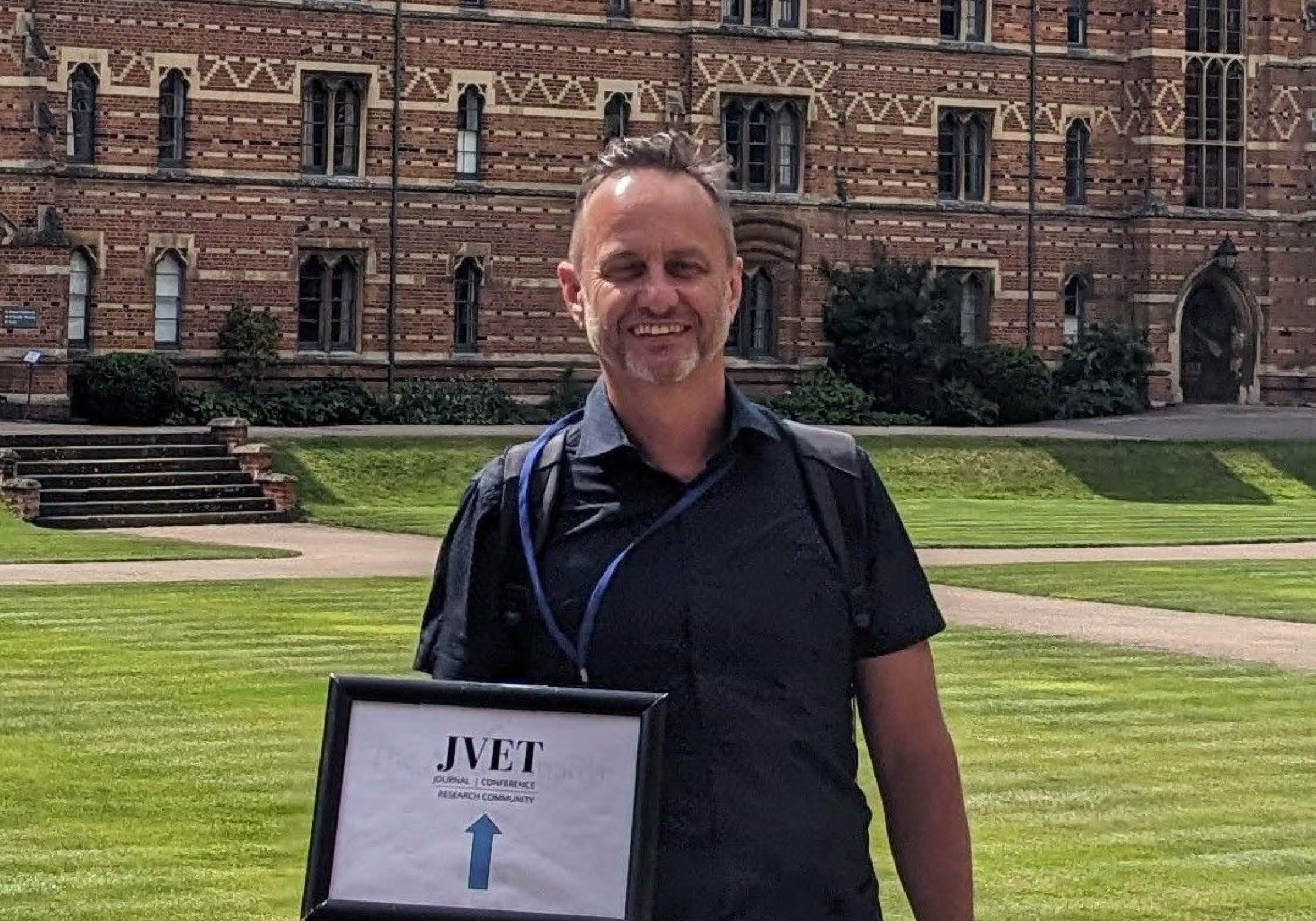 Person standing in front of building holding sign