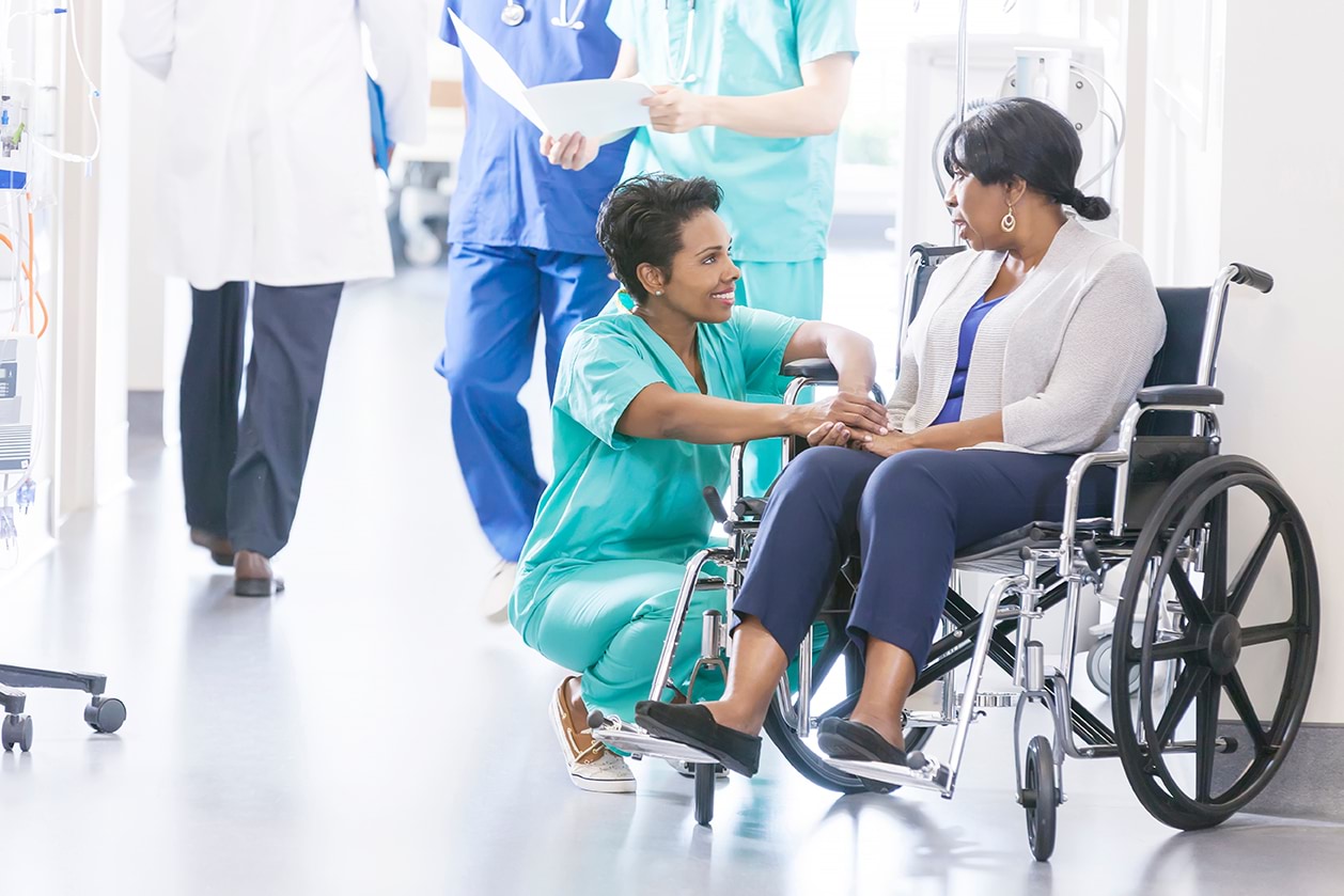 A nurse of African background speaks with an elderly patient who is also from African background