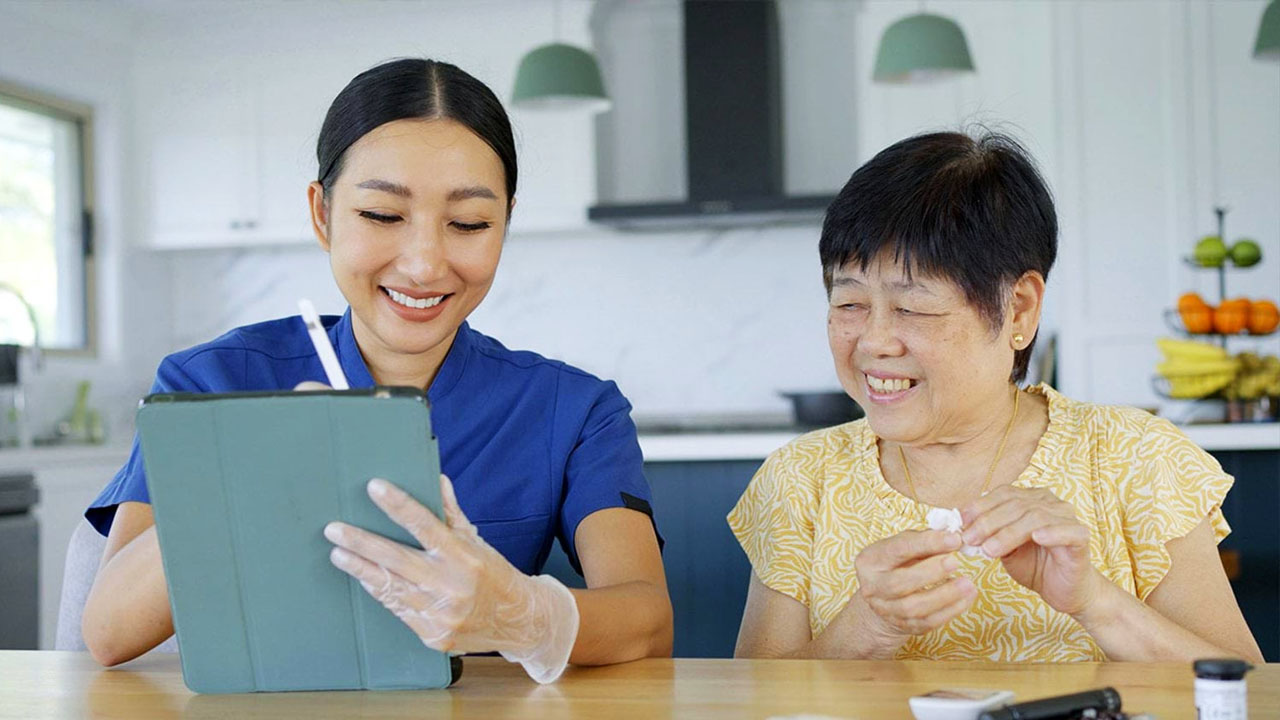 Health care worker and client looking into hand held device in home setting