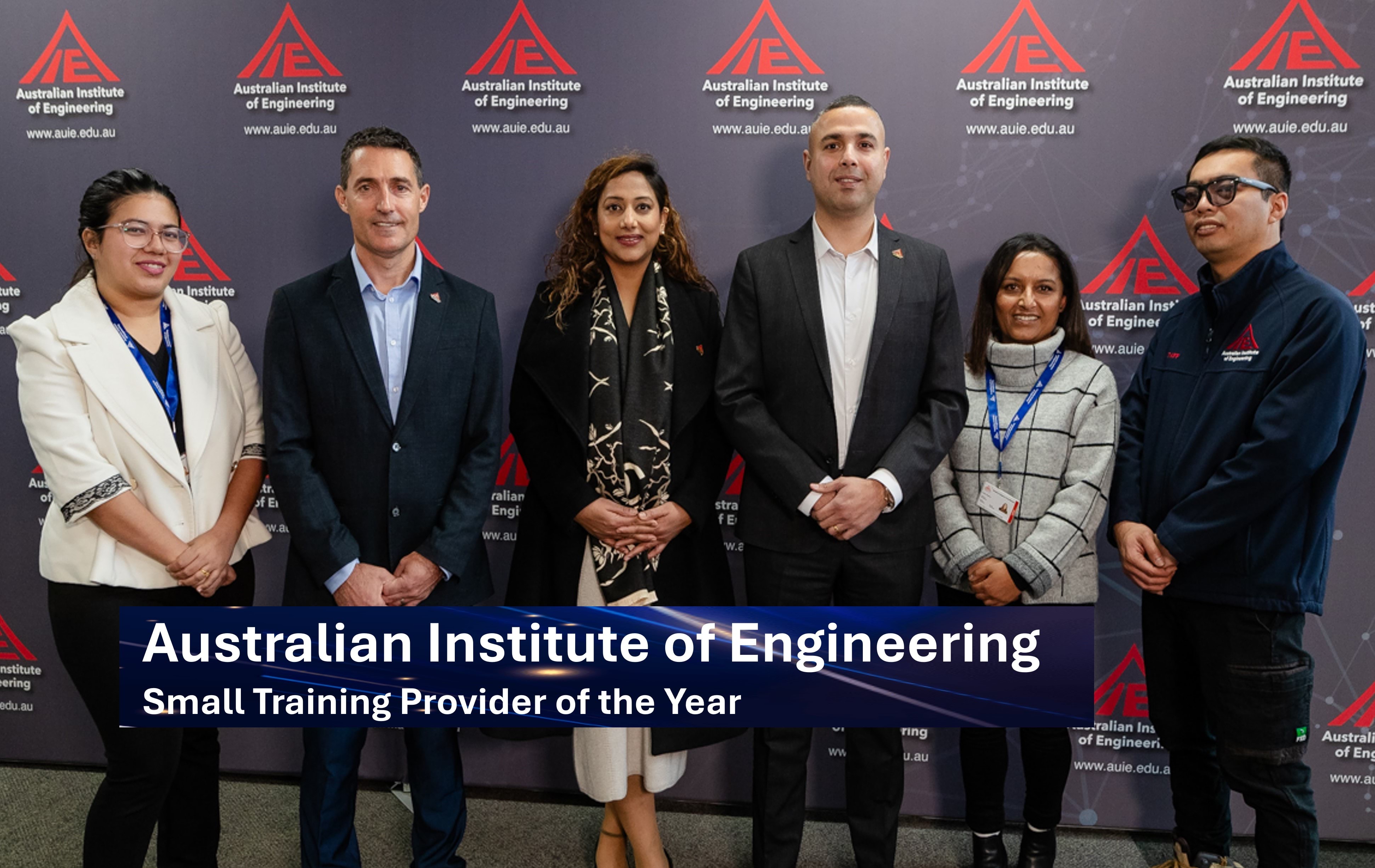 Employees smiling and standing in front of a banner